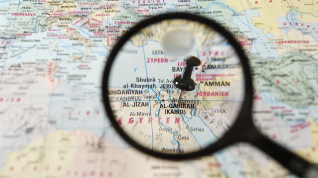 Magnifying glass highlights Cairo on a paper map of Europe