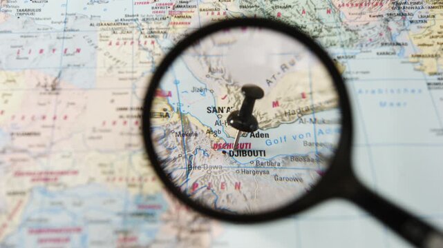 Magnifying glass highlights Djibouti on a paper map of Europe