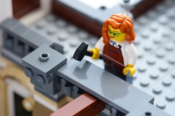 Fototapeta premium Tambov, Russian Federation - June 24, 2026 A Lego redhair woman minifigure with a hammer in a gray building. Close-up
