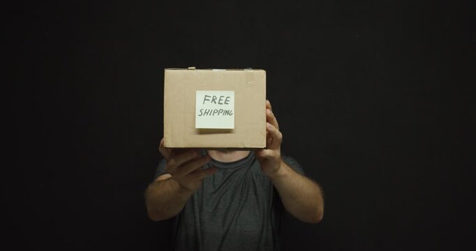 Man holding a cardboard package with a "Free Shipping" label toward the camera. Ideal for ecommerce, parcel delivery, shipping, and online shopping concepts.