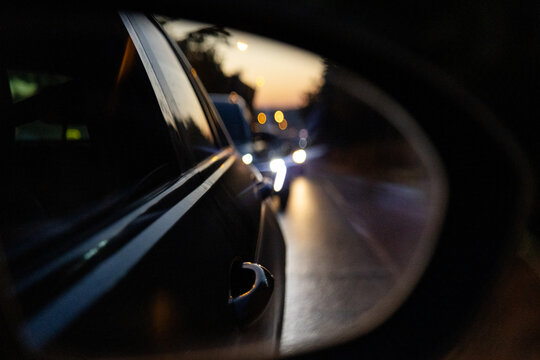 Car side mirror reflect evening traffic on urban road