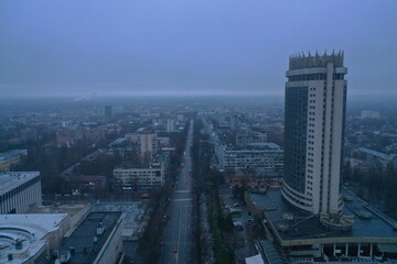 Fototapeta premium Aerial view of urban skyline with tall building and misty streets at dawn