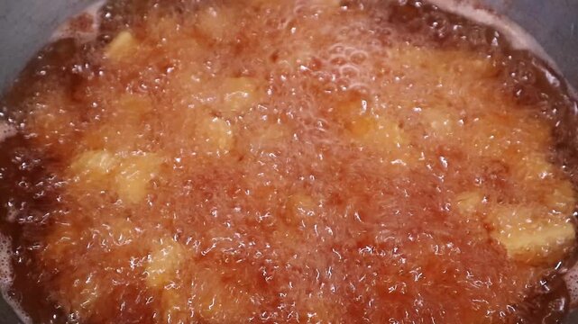 Close up of delicious apple pieces simmering in a sweet caramel sauce in a pan.