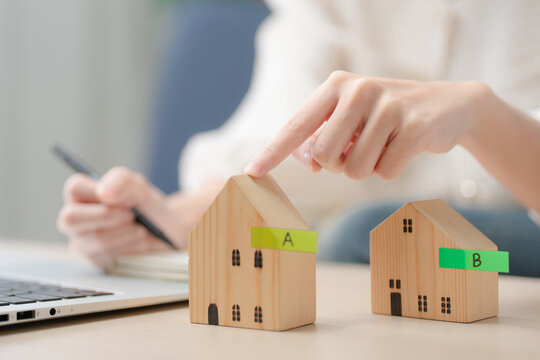 Home comparison concept. Person comparing two house models to choose the best property while planning a purchase. Real estate, home buying, comparison, property, investment