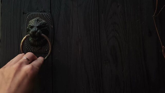 woman knocks with a vintage metal door knocker on a dark wooden door, traditional entrance, home access, rustic architecture, close up.