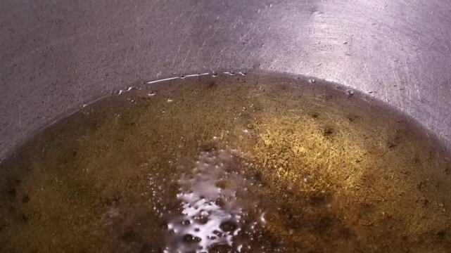 Hot cooking oil bubbling in a metal pan for deep frying.