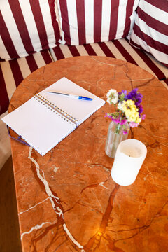 Notebook and flowers on marble cafe table with candle