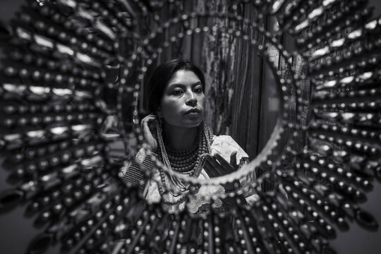 Woman reflected in mirror with beads and ornate costume
