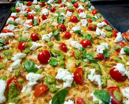 Colorful tray pizza or pinza in artisanal bakery in Rome, food of Italy, street food for lunch, with tomatoes, salami, basil, mozzarella