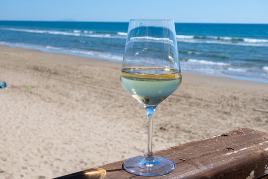 Chilled glass of white wine and sandy beach near Sperlonga, Italy, relaxed seaside holiday atmosphere near popular coastal resort town