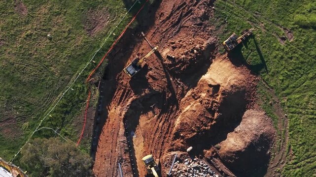 Rotating aerial shot of excavators digging trenches on a construction site