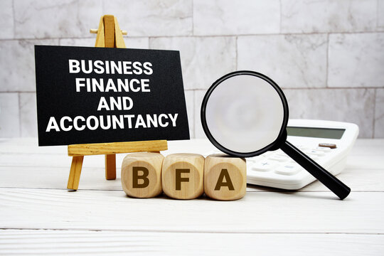 BFA Business Finance and Accountancy text with calculator magnifying glass and on wooden background