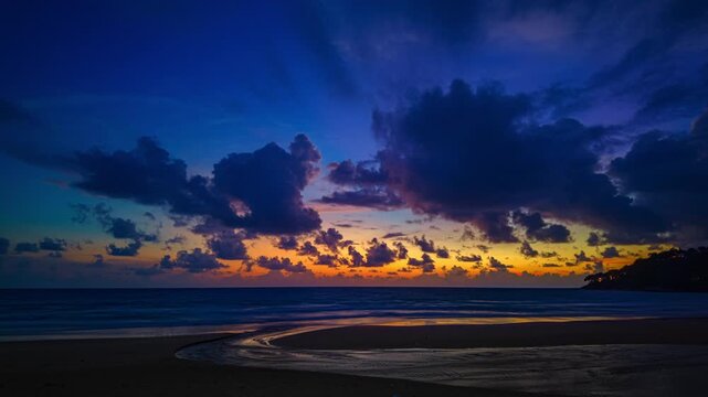 Time lapse sky turns yellow to orange and red over the sea.
The sun rays cast a warm glow on the landscape. The horizon is painted in hues of red and purple. The sky is ablaze with color