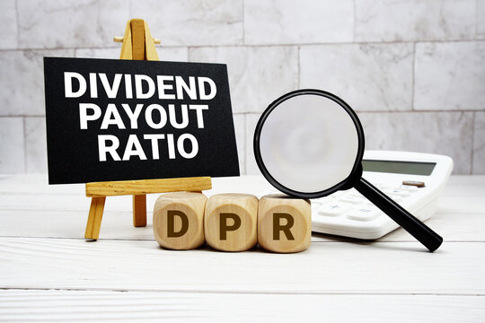 DPR Dividend Payout Ratio text with calculator magnifying glass and on wooden background