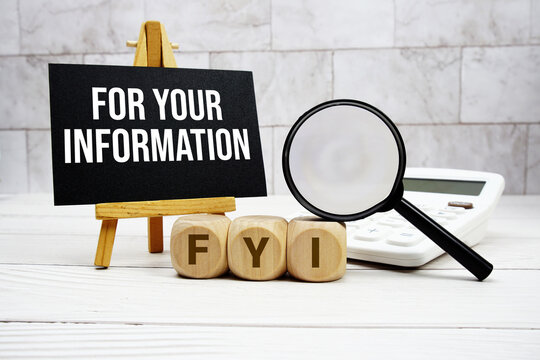 FYI For Your Information text with calculator magnifying glass and on wooden background