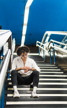 Man check wristwatch while sit on city subway stairs