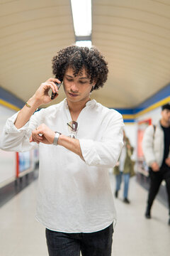 Man check wristwatch while talk on smartphone in subway