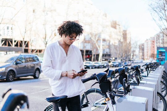Man use smartphone beside city bike share station