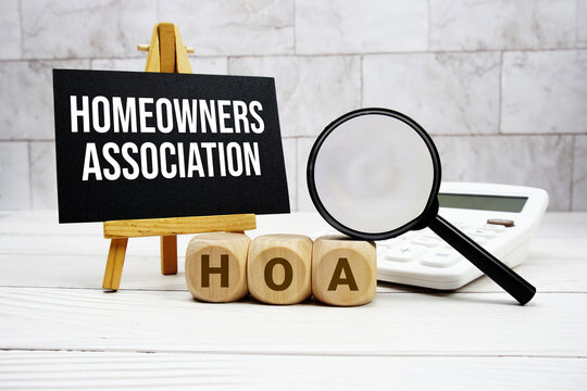 HOA Homeowners Association text with calculator magnifying glass and on wooden background