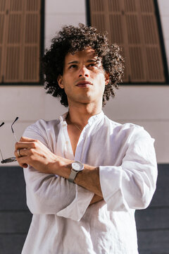 Confident man in white shirt standing in city sunlight