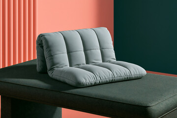 Obraz premium A quilted gray cushion resting on a dark green upholstered bench against a two-tone wall backdrop