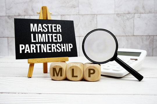 MLP Master Limited Partnership text with calculator magnifying glass and on wooden background