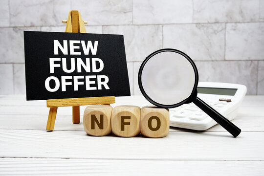 NFO New Fund Offer text with calculator magnifying glass and on wooden background