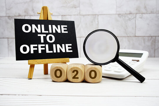O2O Online to Offline text with calculator magnifying glass and on wooden background