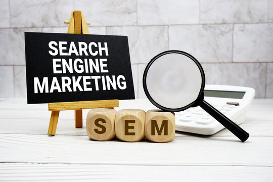 SEM Search Engine Marketing text with calculator magnifying glass and on wooden background