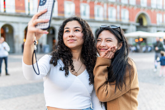 Friends take a smartphone selfie in urban Madrid square