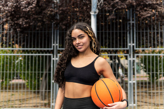 Young woman hold basketball on outdoor court