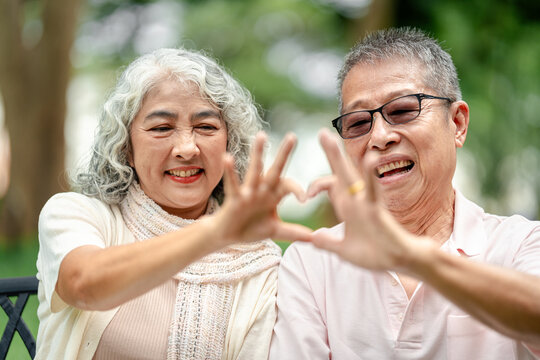 Senior couple radiating happiness showing love heart gesture han