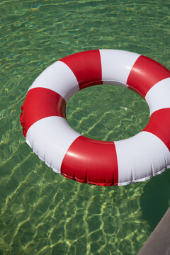 Red and white striped pool float in sunny water