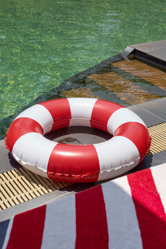 Red and white pool float beside turquoise water