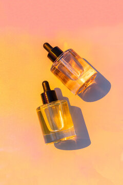 Cosmetic facial serum bottles on warm color background