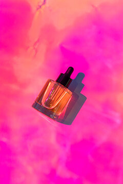 Cosmetic facial serum bottle with vivid pink background