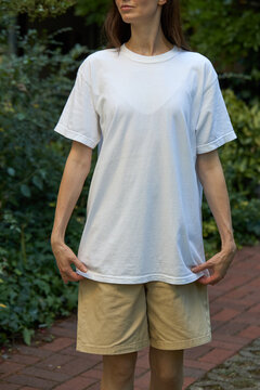 Woman wearing a plain white t-shirt and tan shorts outdoors