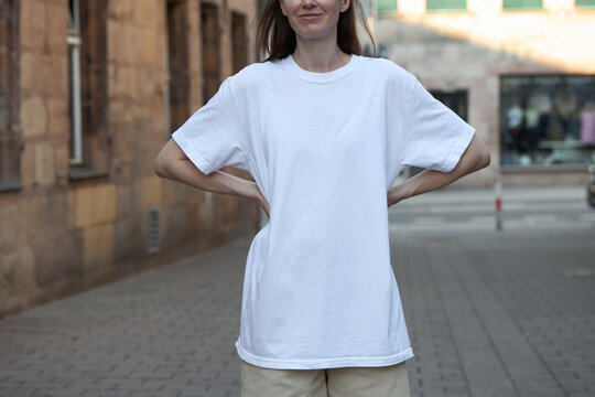 Woman wearing a plain white t-shirt and striped shorts on a city street