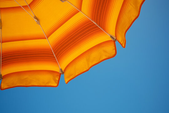 Orange beach umbrella against clear blue sicilian sky