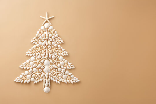 Seashell Christmas tree with starfish on beige background. Tropical Christmas, coastal summer holiday, beach decor, flat lay image with copy space