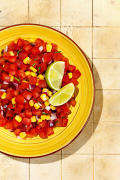 Fresh Mexican salsa with lime on yellow ceramic plate