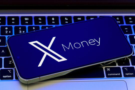 X Money branding and X logo displayed on a smartphone placed across a laptop keyboard in a digital payments concept. Stafford, United Kingdom, August 2, 2026.