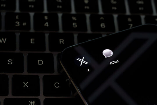 XChat and X app icons displayed on a smartphone resting on a laptop keyboard in a messaging technology illustration. Stafford, United Kingdom, August 2, 2026.