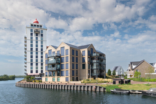 Modern waterfront apartment buildings, including the landmark De Vuurtoren tower, beside a canal in the Waterfront district of Harderwijk, the Netherlands. Vertical photo.