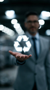 Businessman in suit showcasing recycling symbol with a blurred background.
