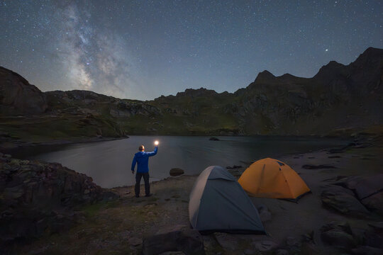 Milky Way night sky over mountain lake camping scene