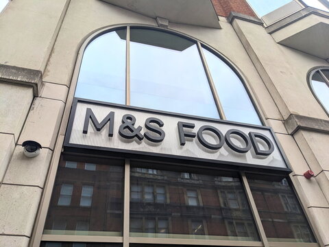 Low angle view of the M and S Food storefront sign on a stone building facade in central London