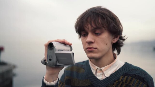 Young filmmaker, vintage MiniDV camcorder, outdoor recording, retro video aesthetics for independent cinema, nostalgic storytelling, media education and creator culture.