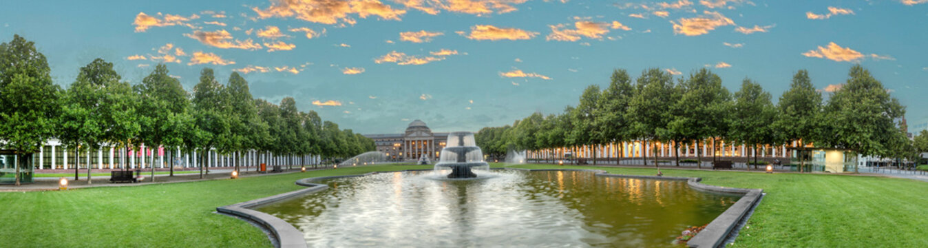 view at bowling green to kurhaus and casino  in Wiesbaden with fountain in foreground and dramatic sunrise sky