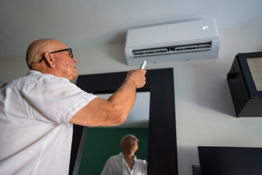 Senior man use air conditioner remote during heatwave